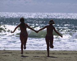 Two people running hand in hand near ocean