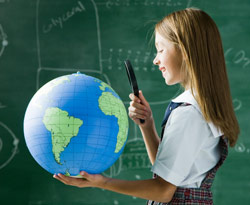 Girl holding magnifying glass looking at globe