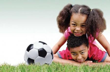 2 kids on grass with a soccer ball