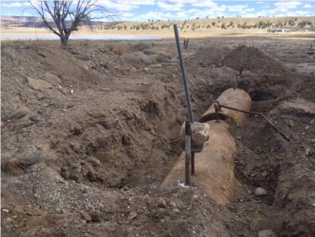 Rusty, cylindrical tank being excavated from desert landscape.
