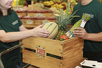 people placing produce in a box