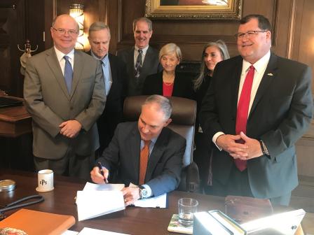 Administrator Pruitt is seated at a desk signing the Mississippi Phosphates Action Memorandum with Pascagoula, Miss. Mayor Dane Maxwell and members of the EPA Office of Land and Emergency Management looking on.