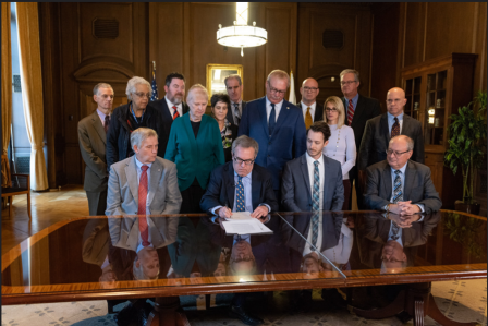 Wheeler signing oil and gas MOU at table.