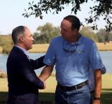 EPA Administrator Scott Pruitt shakes hands with Ted Kendall, owner of Gaddis Farms, under a tree near a lake