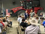 Administrator Pruitt speaks with a man while tables of others look on.  There is a tractor in the background.