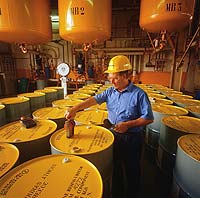 Photograph of a worker labeling large metal containers.