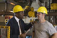 Photograph of two workers having a conversation in an industrial setting.