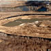 1987 photo (looking east) depicting the manipulation of the Blackstone River by private sand  and gravel extraction and landfilling operations at the Un-named Island immediately  south of the J.M. Mills Landfill and a part of the OU2 investigation. (Large excavator in operation at center of photo; Blackstone River splits its flow around island; access to island is  via the Pratt Dam off photo to the right).