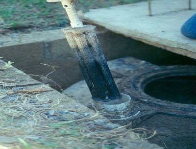 The photo shows a biotube filter fully extracted from a septic tank.
