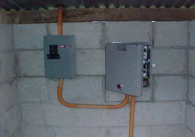 The photo shows the metal fuse and control boxes mounted on a concrete block wall inside the shelter.