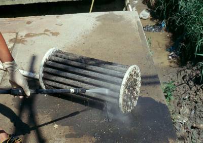 The photo shows a person pressure spraying a pump vault filter.