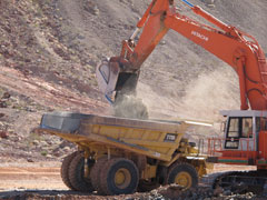An over-sized backhoe loads construction aggregate into an equally large dumptruck at the closure site