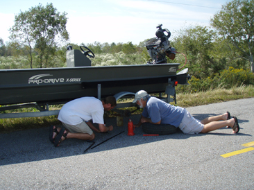 survey field personnel changing a flat tire on a boat trailer