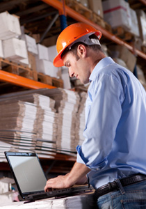 photo of a man using laptop in a warehouse