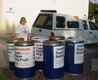 woman standing behind recycling containers